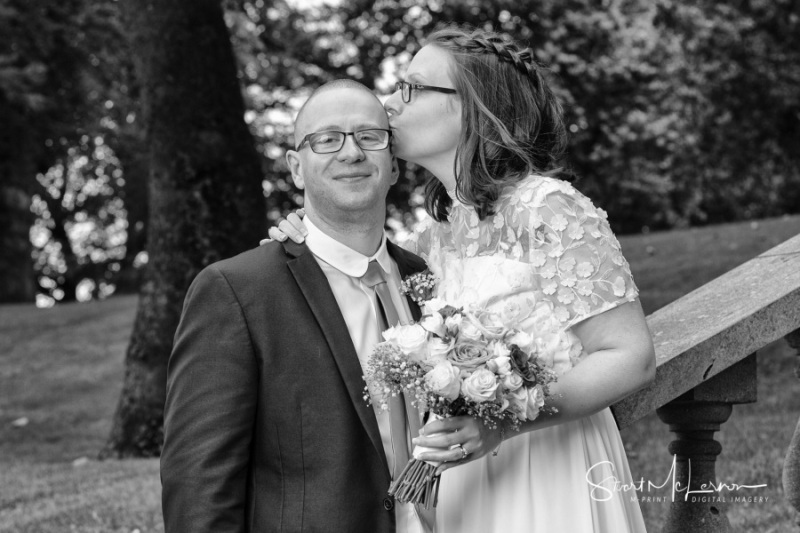 Bride kissing Groom's head at Dukinfield Park