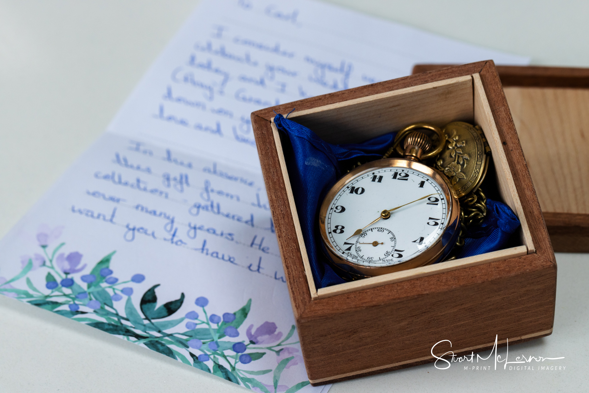 The groom's pocket watch in a presentation box on top of a letter from his bride-to-be