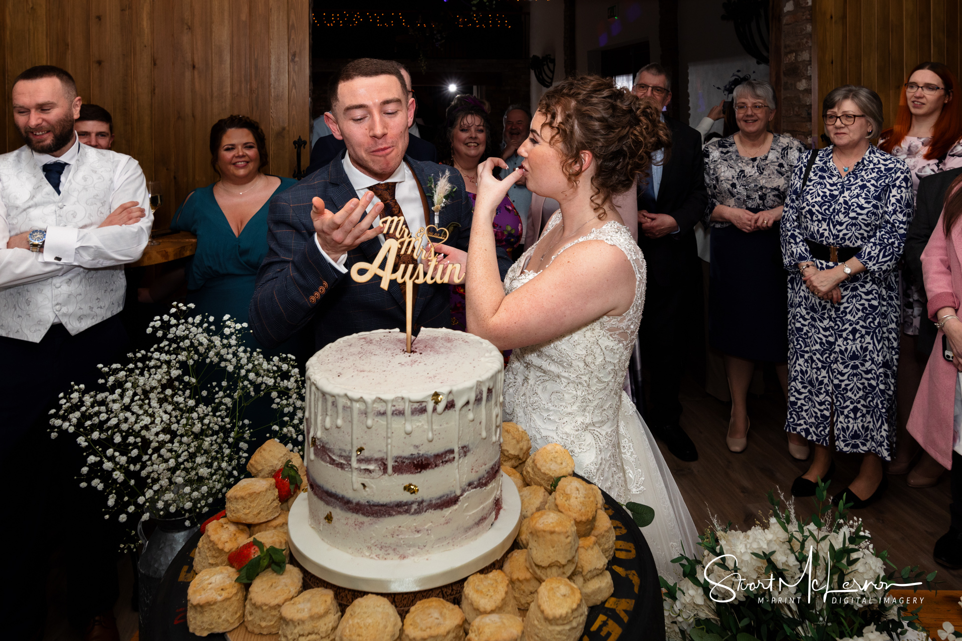 The bride and groom lick their fingers after cutting the cake