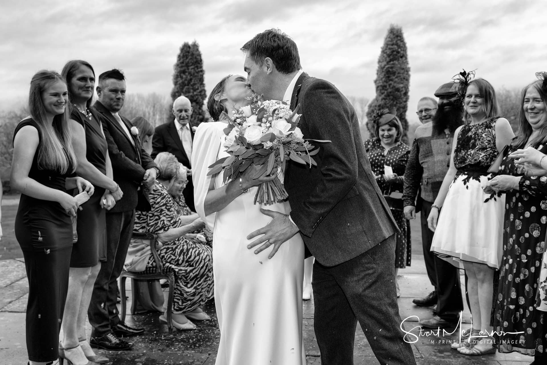 The bride and groom perform a Hollywood kiss during their confetti walk outside Crewe Hall