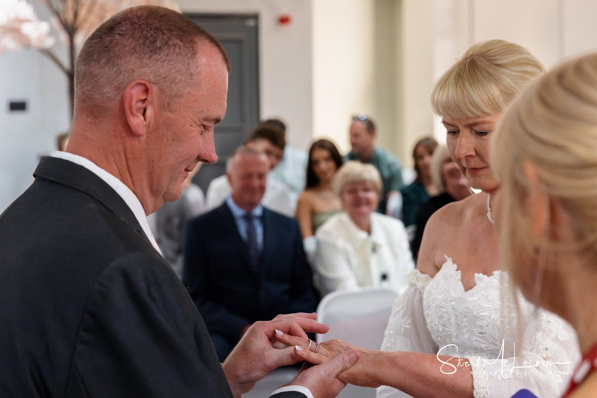 The groom places a wedding ring on the finger of his bride at The Village Hotel Cheadle.