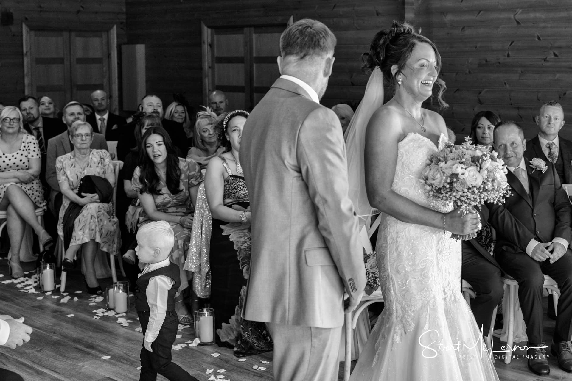 The guests laugh as the couple's child wanders during their wedding ceremony at Styal Lodge